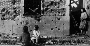 Fotografía de Robert Capa. Los niños hablan ajenos a la guerra ante la fachada destrozada por la metralla del número 10 de la calle Peironcely, November-December 1936 ©International Center of Photography/Magnum Photos.